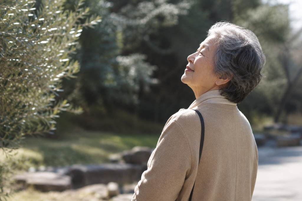 クリスマス会で祈りを受け、穏やかな表情で空を見上げる80代女性